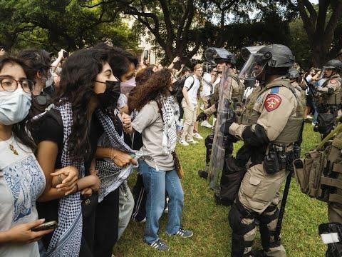 On a campus, students, arms linked, lined up facing riot police in helmets, batons and shields.