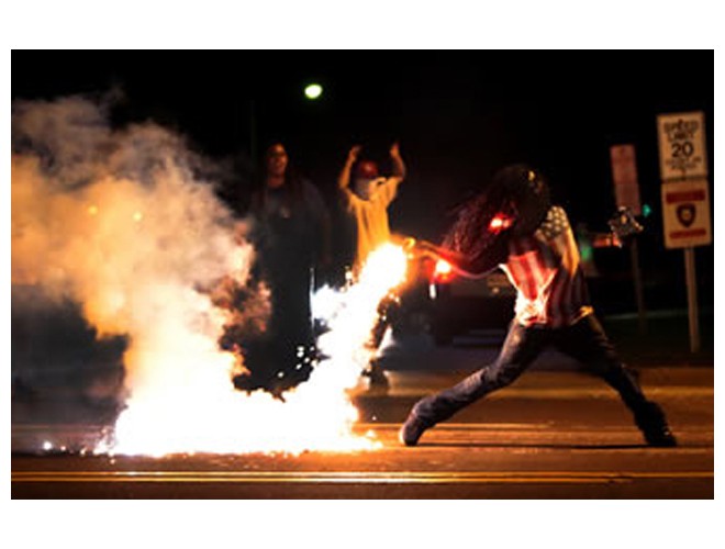 Protester throws back a tear gas canister that the police had fired at the people, Ferguson, August 13. Photo: AP Protester throws back a tear gas canister that the police had fired at the people, Ferguson, August 13. Photo: AP