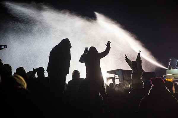 Protestors stand defiant against water cannons.