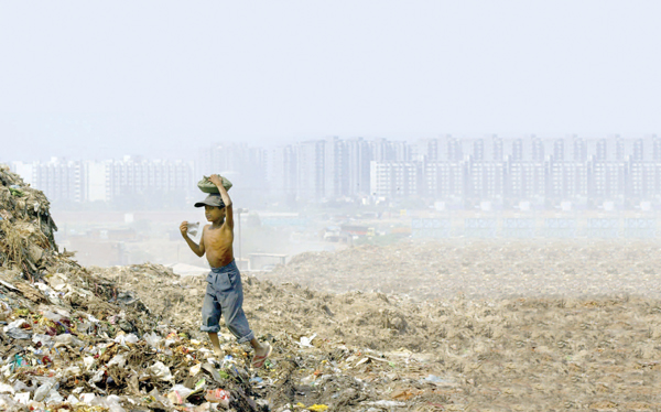 A boy in Delhi, India scavenges in a garbage dump to feed his family.
