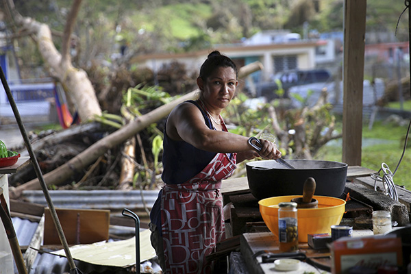 A resident of Yabucoa, Puerto Rico cooks outside over a wood fire since electric power was wiped out by Hurricane Maria