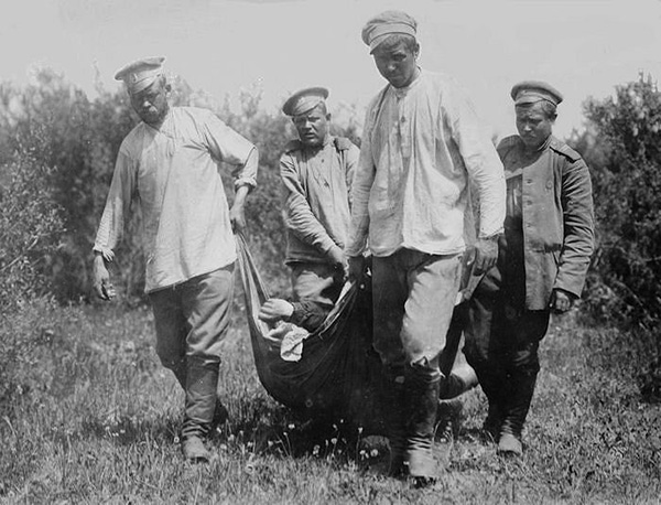 Cuatro hombres arrastran un cuerpo por un campo.