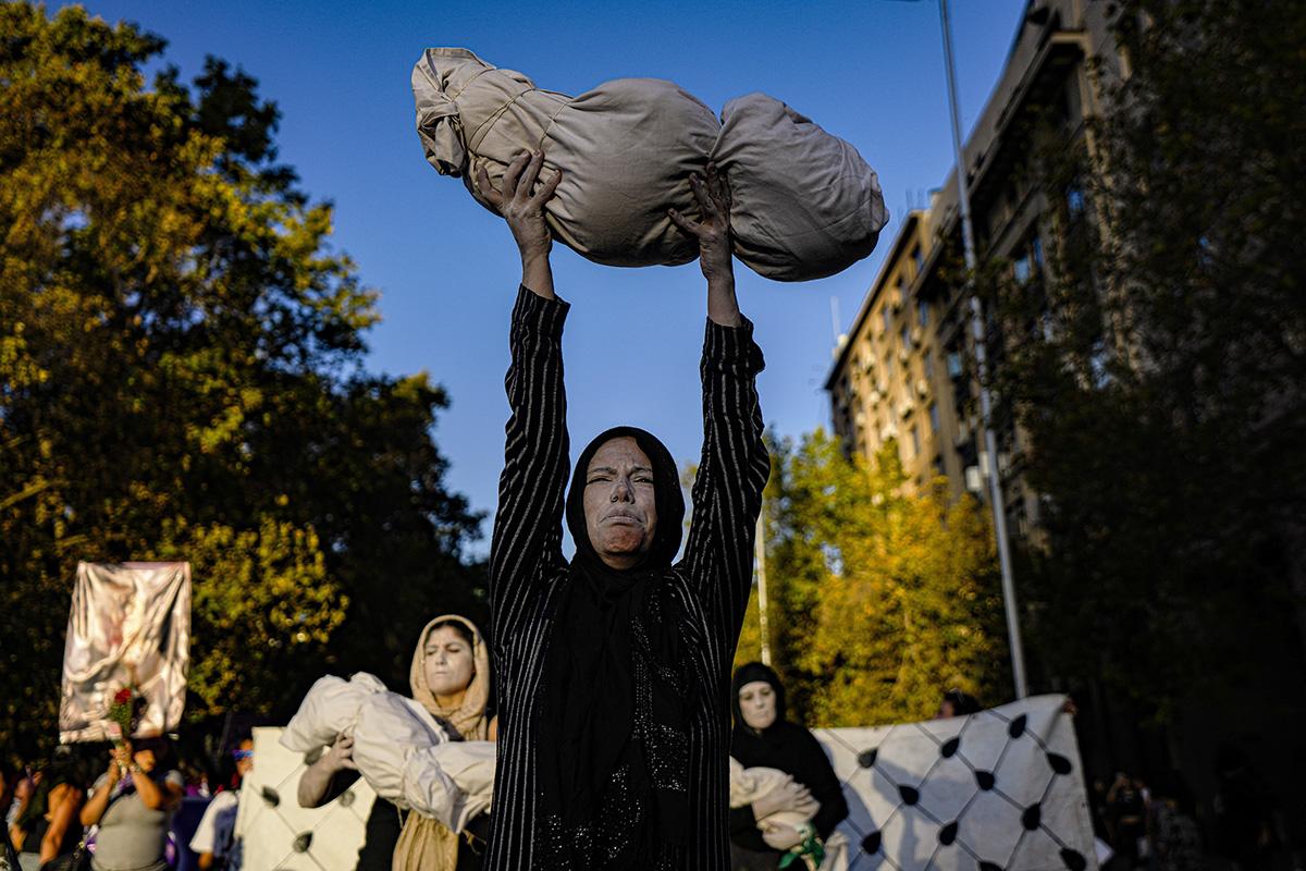 Chilean women hold swaddled dolls that represent the children killed in Gaza, protesting U.S.-backed Israeli genocide.