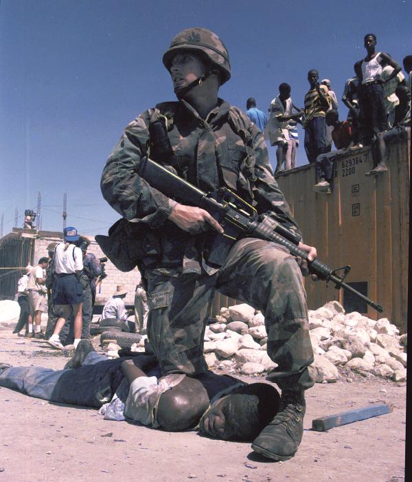 U.S. Marine kneels on back of Haitian during 1994 invasion of Haiti.